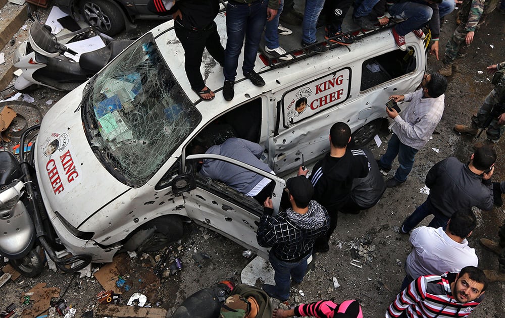 Hezbollah investigators inspect a destroyed car at the site of a car bombing in a southern suburb of Beirut, Lebanon. The bomb ripped through a Shiite neighborhood, killing several people and setting plumes of smoke over the area in the latest attack targeting supporters of the militant Hezbollah group in Lebanon.