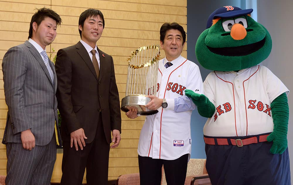 Japanese Prime Minister Shinzo Abe, second right, holds the World Series trophy brought to Japan by Boston Red Sox pitchers, Junichi Tazawa, left, and Koji Uehara, second left, and Red Sox mascot Wally the Green Monster during their visit to Abe`s official residence in Tokyo.