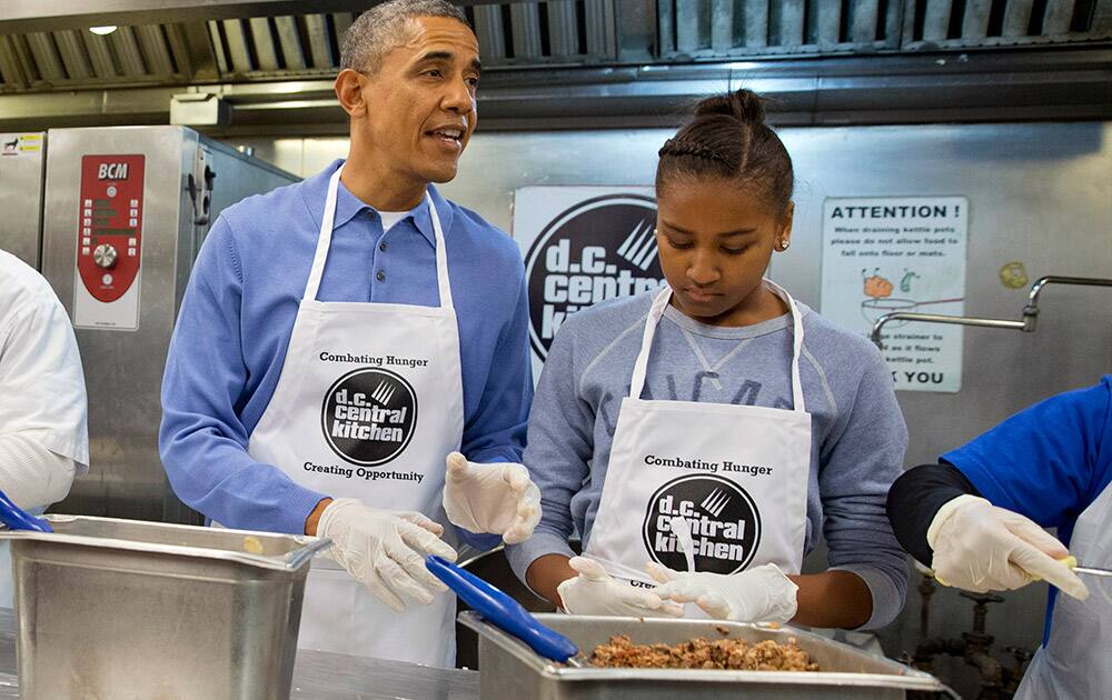 President Barack Obama and his daughter Sasha, right, make burritos at DC Central Kitchen as part of a service project in honor of Martin Luther King, Jr. Day, in Washington. Also helping were first lady Michelle Obama and daughter Malia Obama.