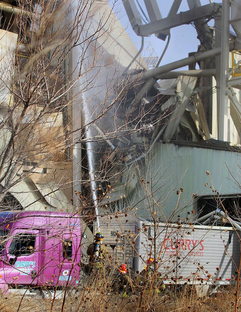 Firefighters spray water outside the International Nutrition plant in Omaha, Neb., Monday, where a fire and explosion took place. At least nine people have been hospitalized and others could be trapped at the animal feed processing plant.