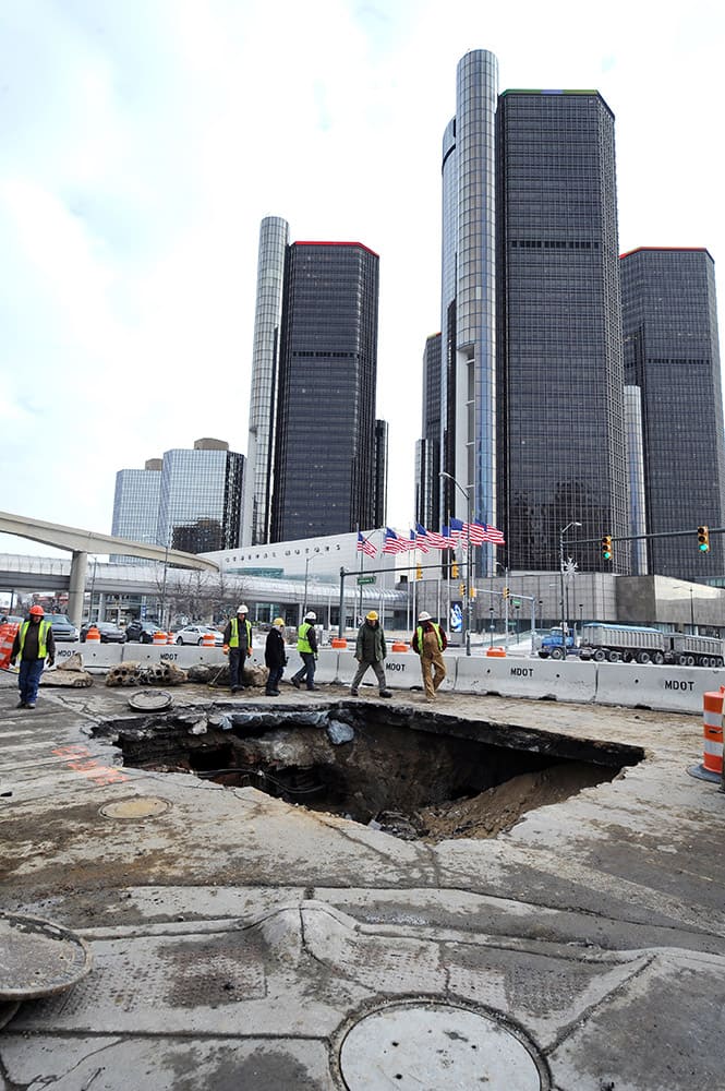 Work crews examine a 14-feet-deep sinkhole that opened up in downtown Detroit over the weekend. Officials learned there was a water main break about 14 feet underground, which caused the surface to collapse, according to the Detroit News.