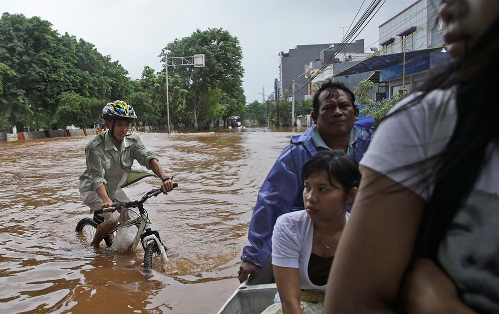 A man navigates his bicycle through floodwaters in Jakarta, Indonesia. Seasonal rains and high tides in recent days have caused widespread flooding across much of Indonesia.