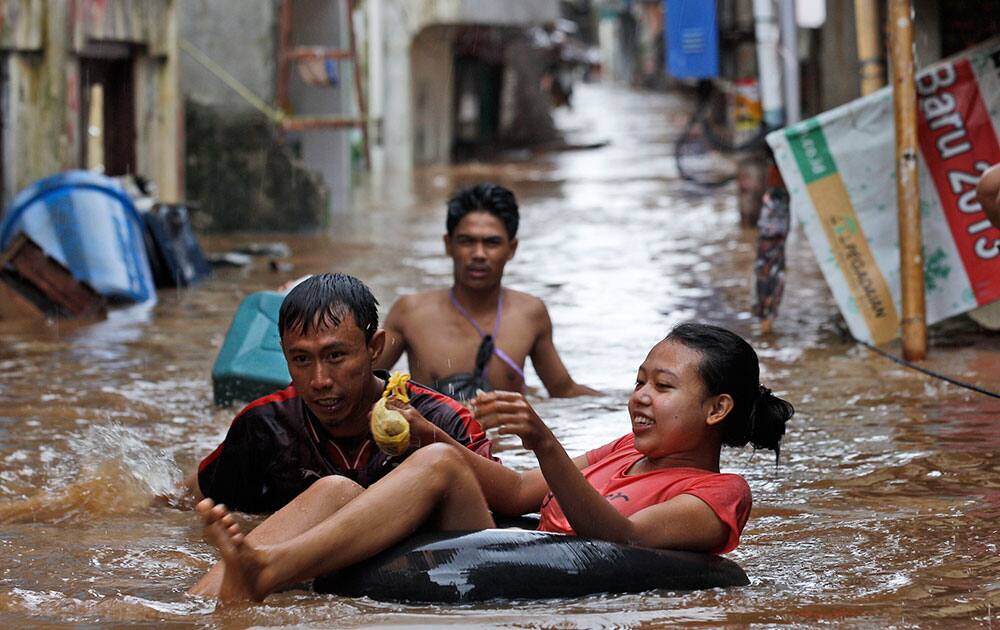 Indonesians wade through a flooded area in Jakarta, Indonesia. Seasonal rains and high tides in recent days have caused widespread flooding across much of Indonesia.