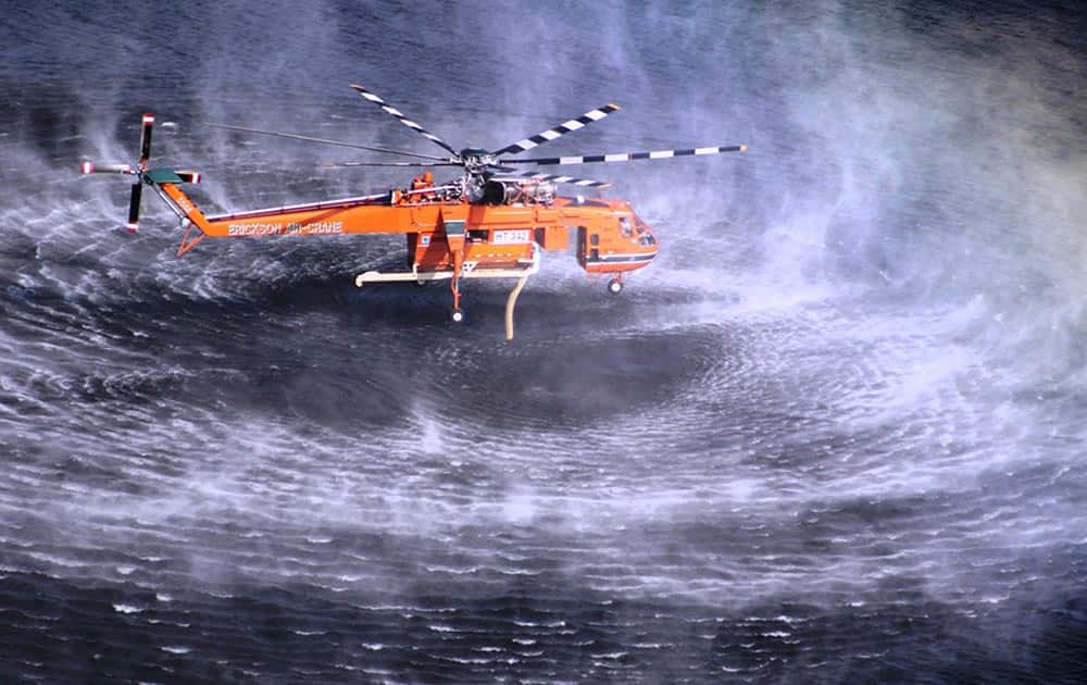 This photo released by Victoria Country Fire Authority, a water bomber hovers above water while it works on a large fires burning throughout Victoria`s Grampians region.