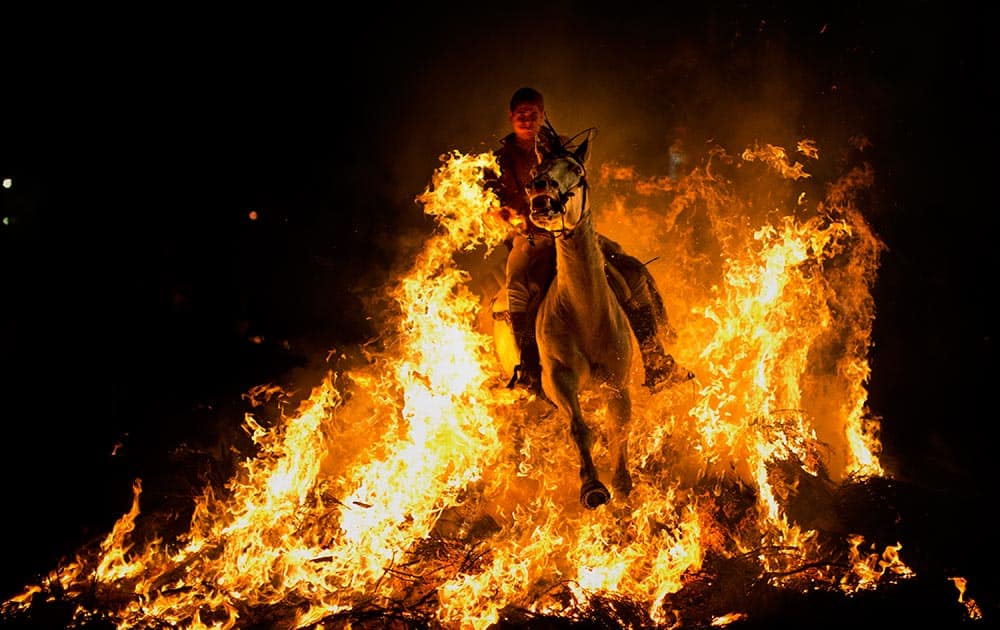 A man rides a horse through a bonfire as part of a ritual in honor of Saint Anthony, the patron saint of animals, in San Bartolome de Pinares, about 100 km west of Madrid, Spain.