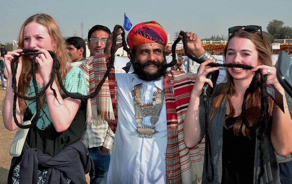 Foreign tourists amuse with the mustache artist during 21st International Camel Festival -2014 in Bikaner.