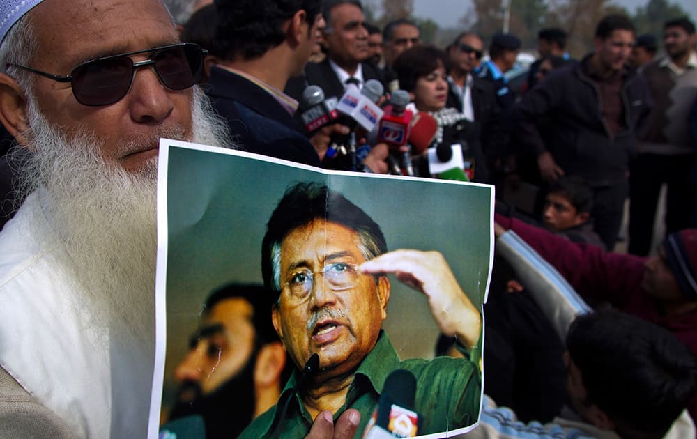 A supporter of Pakistan`s former president and military ruler Pervez Musharraf holds a poster with a photo of him during a news conference with Musharraf`s lawyers outside the special court in Islamabad,.