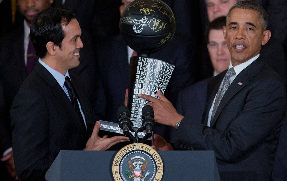 President Barack Obama points to his name on a commemorative trophy giver to him by Miami Heat head basketball coach Erik Spoelstra during a ceremony in the East Room of the White House.