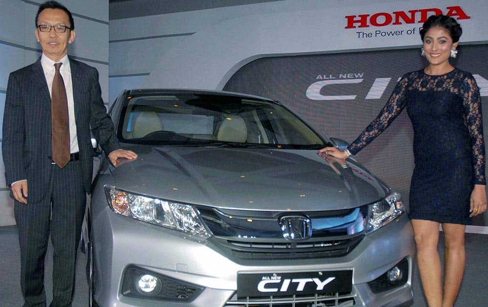 Shigeru Yamazaki,Senior Vice President and Director,Sales and Marketing,Honda Cars Limited and model Pamela(R) posing with `New 4th Generation Honda City` during its launch,in Kolkata.