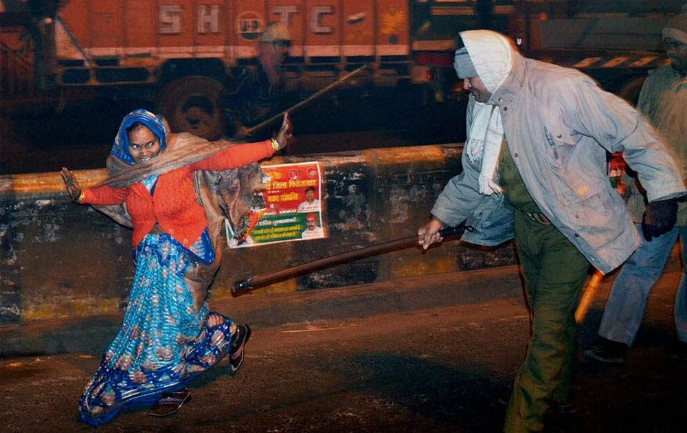 Policemen lathicharging a woman during a protest after an accident on the national highway in Firozabad.