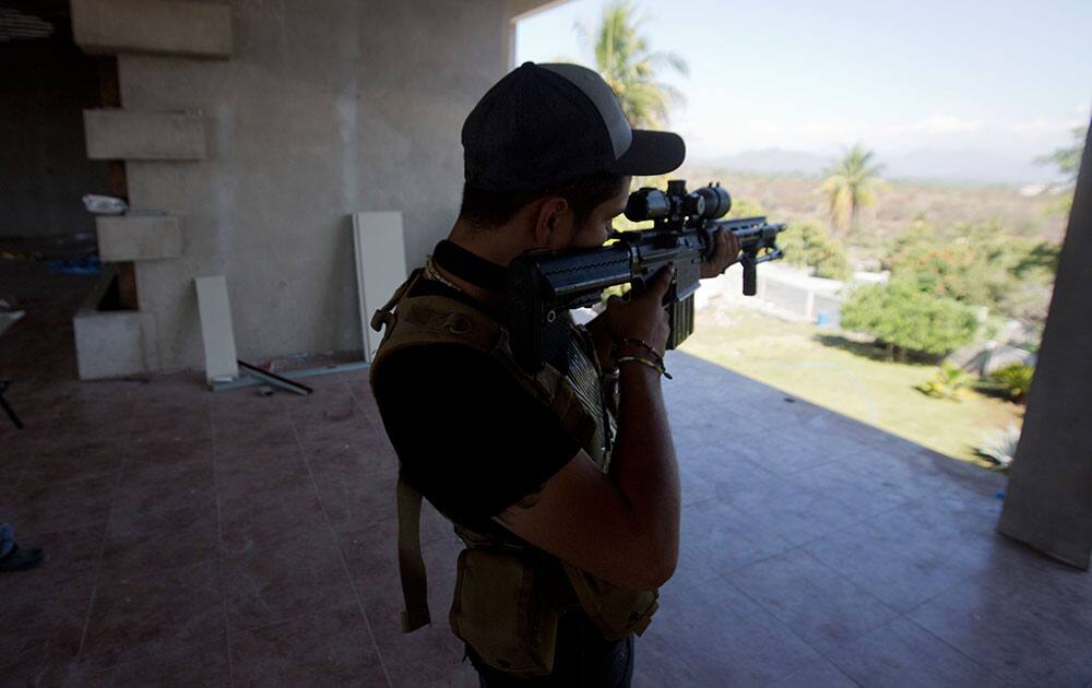 A man belonging to the Self-Defense Council of Michoacan, (CAM), peers through the sight of his weapon at a checkpoint in Nueva Italia, Mexico.