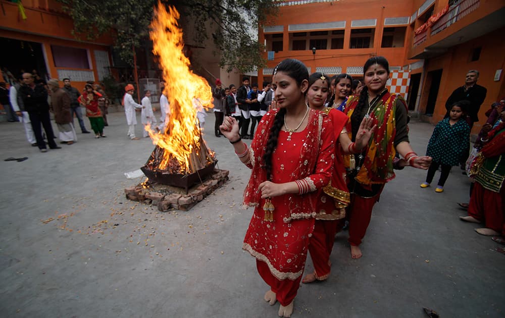 Women dressed in traditional attire dance around a bonfire as they celebrate Lohri festival in Jammu.