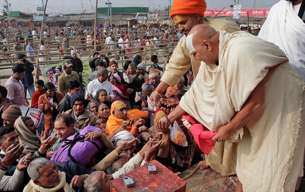 Hindu devotees seek sacred food `Prasadam` and blessing from the priest of Kapil Muni temple in Gangasagar, the confluence of the Ganges River and the Bay of Bengal, about 140 kilometers south of Kolkata. Thousands of devotees arrive at the confluence for the holy dip on the auspicious `Makar Sankranti` day that falls on Jan. 14.