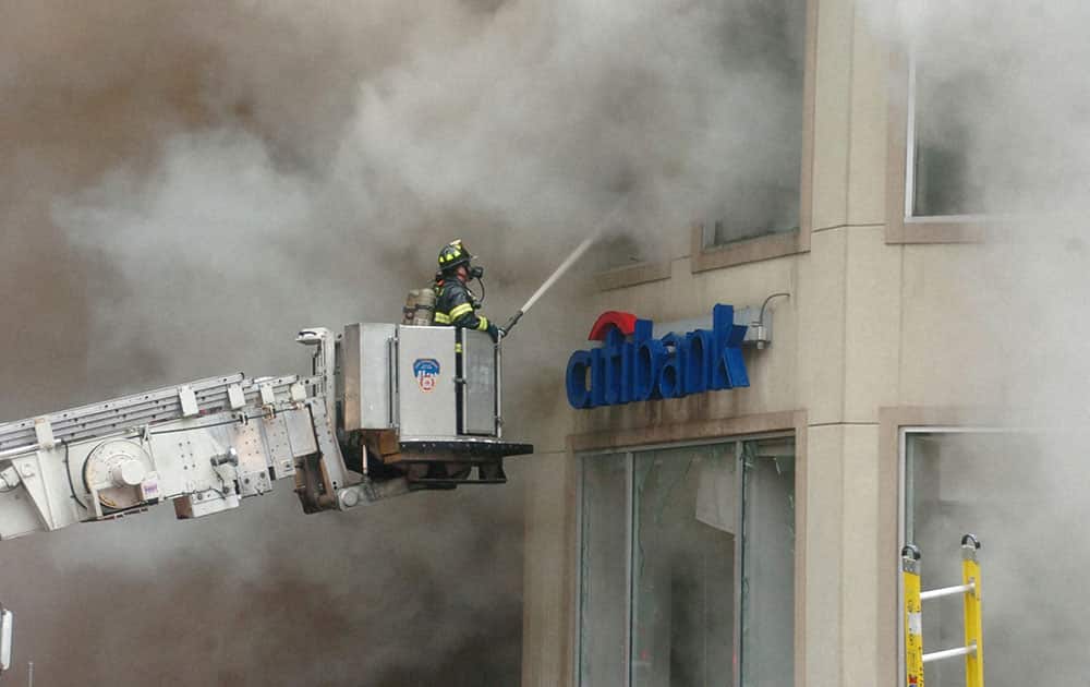 A firefighter from the New York City Fire Department shoots water through second floor window of a Citibank branch as several FDNY companies battle a five alarm fire in the Manhattan borough of New York City.