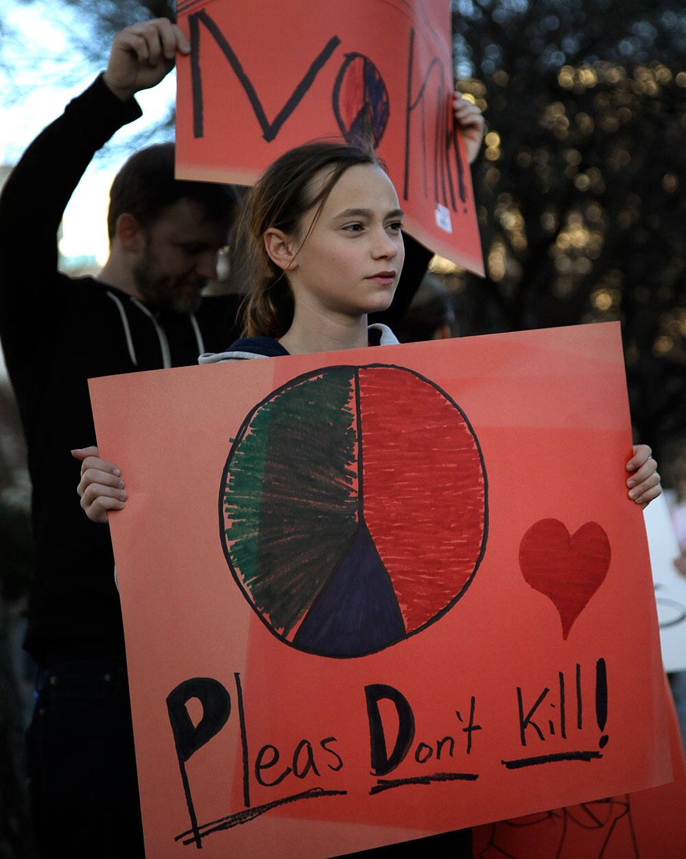 Emma Cokeley, 11, of Dallas, stands with her step father Dan Tossin, rear, as they protest with nearly 40 others outside the Dallas Convention Center where the Dallas Safari Club is holding its` weekend show and auction, in Dallas.