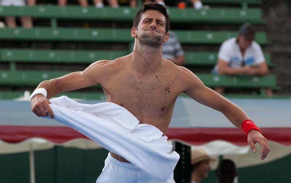 Serbia`s Novak Djokovic jokes with the crowd as he takes his shirt off during his match against Juan Monaco of Argentina at the Kooyong Classic ahead of the Australian Open tennis championship in Melbourne Australia.