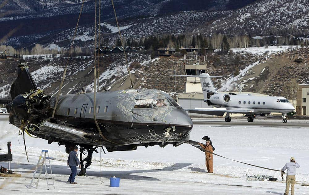 The fuselage of a plane is lifted by crane as the wreckage is removed from a runway, at Aspen-Pitkin County Airport in Aspen, Colo.