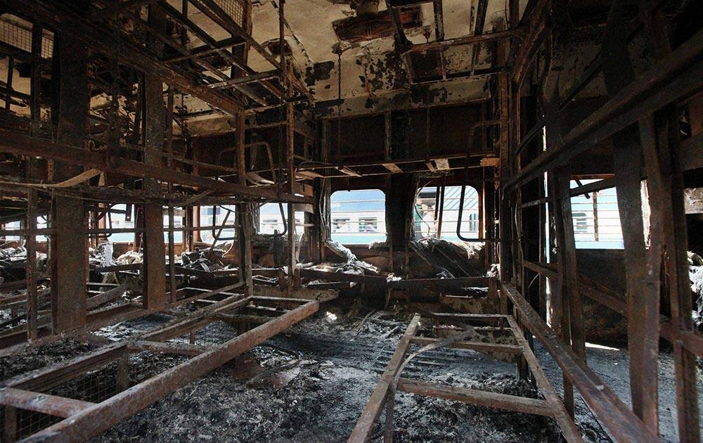 A train moves past a coach of a passenger train that caught fire early Wednesday near Gholvad town, in the western Indian state of Maharashtra.