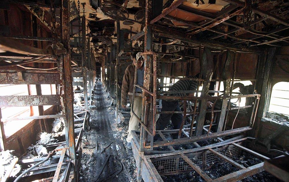 Officers inspect the damage inside a passenger train that caught fire early Wednesday near Gholvad town, in the western Indian state of Maharashtra.