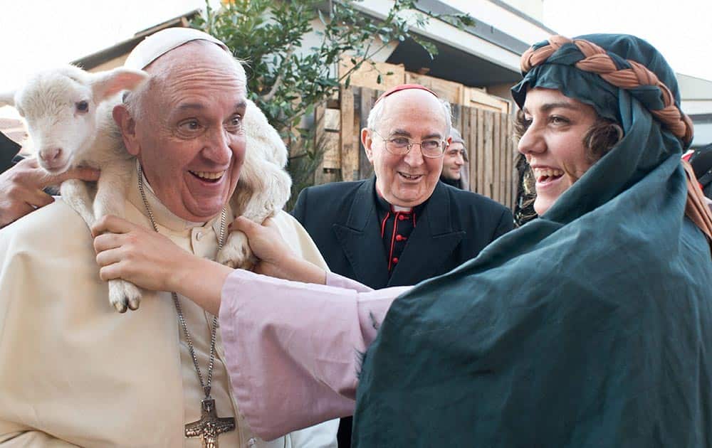Pope Francis is placed a lamb around his neck as he visits a living nativity scene staged at the St. Alfonso Maria de` Liguori parish church, in the outskirts of Rome.