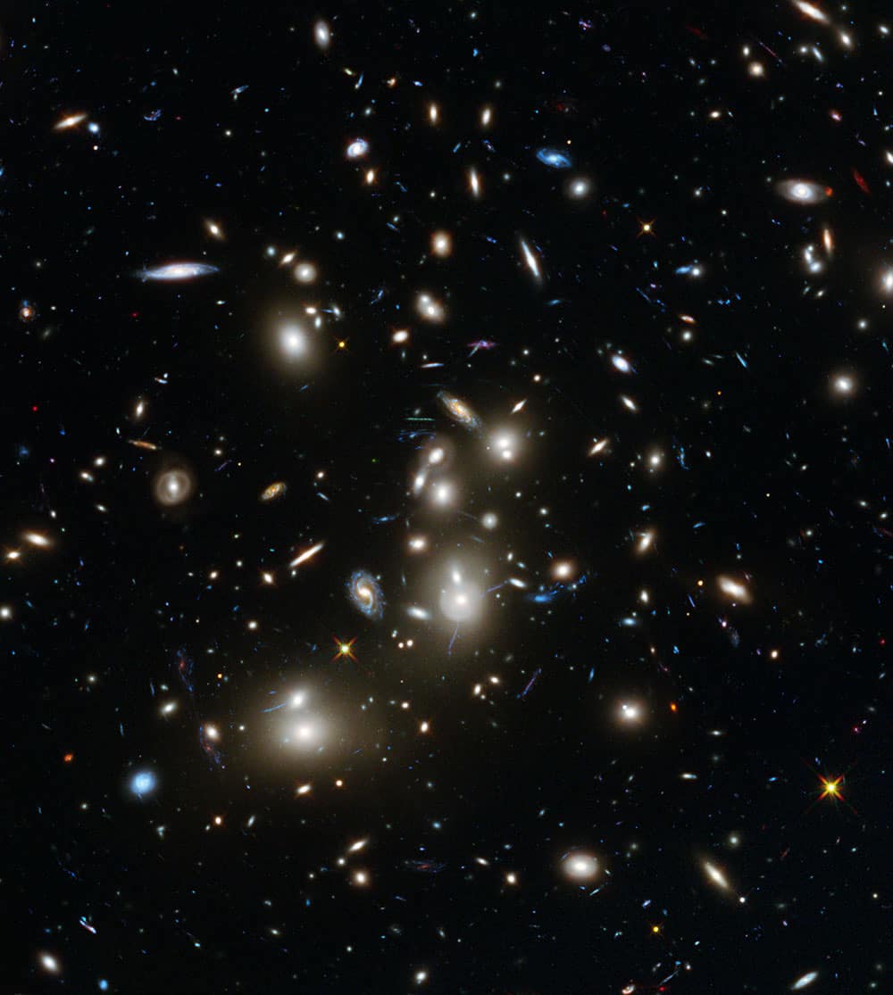 This undated image made available by the European Space Agency and NASA shows galaxies in the Abell 2744 cluster, and blue galaxies behind it, distorted and amplified by gravitational lensing. The long-exposure image taken with NASA`s Hubble Space Telescope shows some of the intrinsically faintest and youngest galaxies ever detected in visible light.