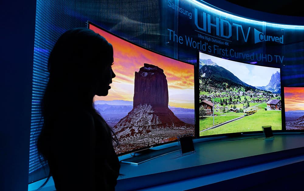 A model stands next to a display of Samsung`s curved 4K UHD TVs during a preview event at the International Consumer Electronics Show in Las Vegas.