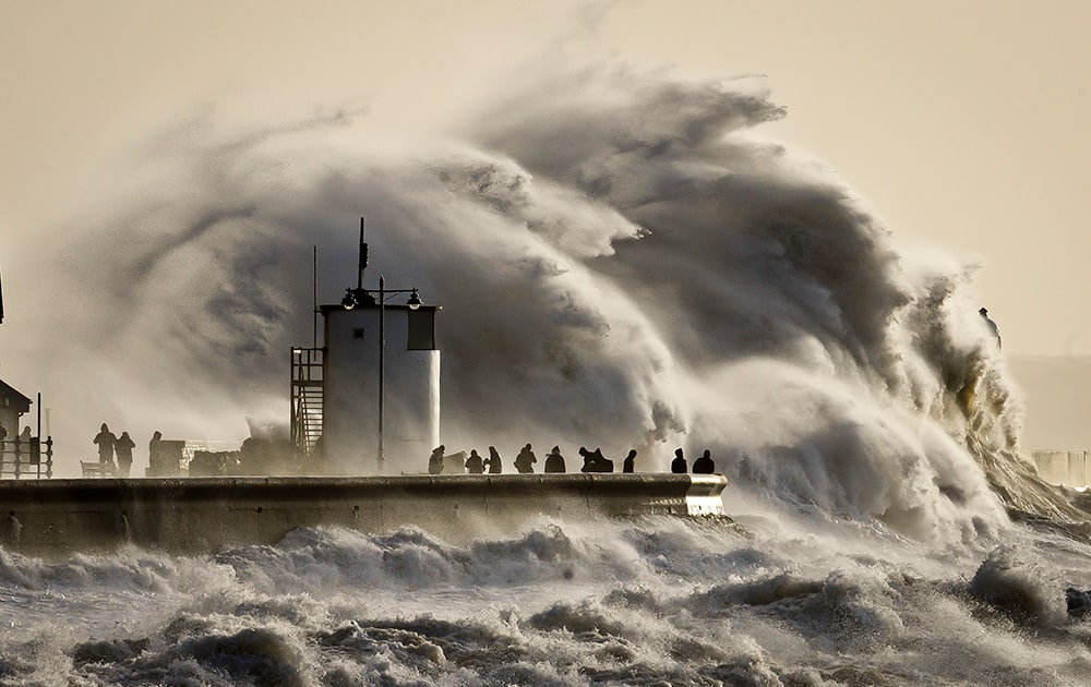 People watch and photograph enormous waves as they break, on Porthcawl harbour, South Wales. Residents along Britain`s coasts are braced for more flooding as strong winds, rain and high tides lash the country.