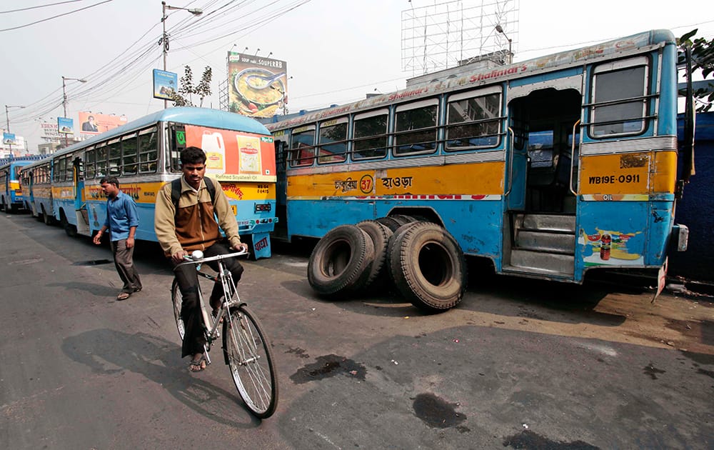 A man rides past parked buses during a 24-hour strike called by private bus transport operators in Kolkata.