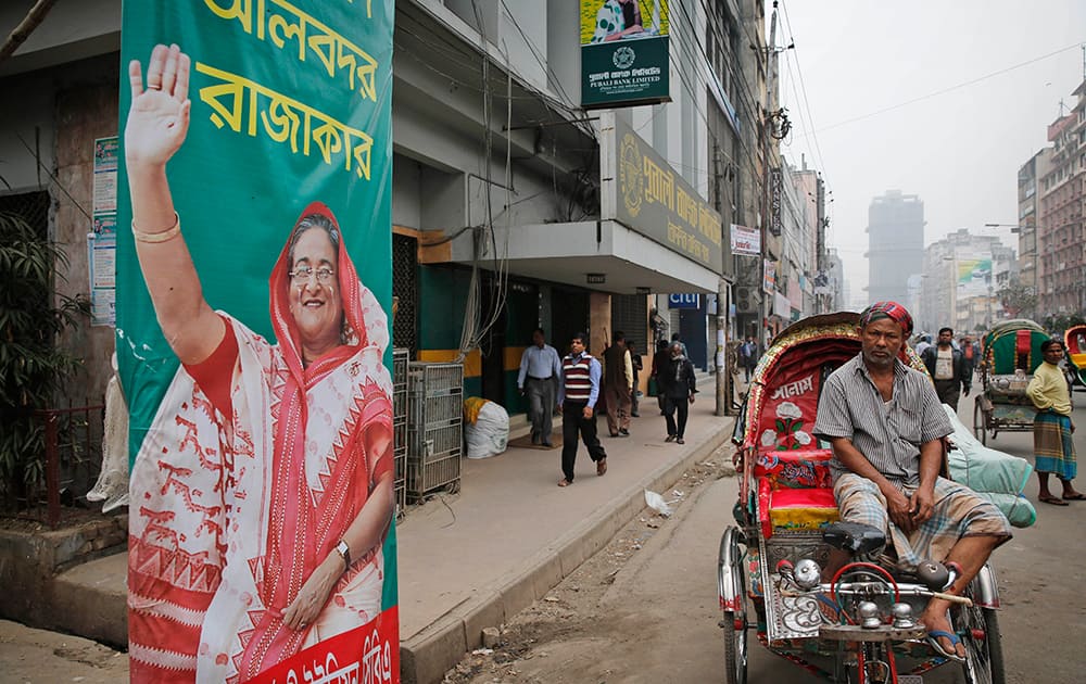 A cycle rickshaw driver waits for customers near a poster of Bangladeshi Prime Minister Sheikh Hasina during a 48-hour general strike called by the opposition to protest Sunday`s election, in Dhaka, Bangladesh.