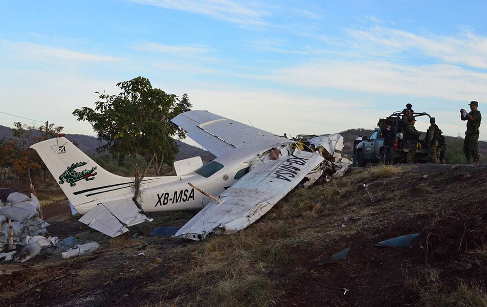 Mexican army soldiers stand next to a single engine aircraft after it crashed near the town of La Huacana, Mexico. The plane crashed in western Mexico, killing one man and injuring four other people, including, Dr. Jose Manuel Mireles, an outspoken doctor who leads a vigilante group, authorities said Sunday.
