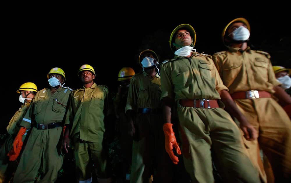 Rescue workers watch as others look for survivors in the debris of a building that collapsed in Canacona, about 70 kilometers (44 miles) from the state capital of Panaji.