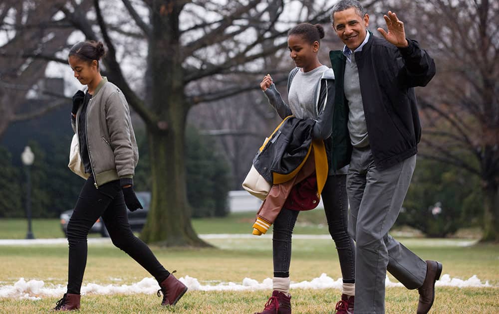 President Barack Obama, right, waves to the media with daughters Sasha and Malia, left, as they return to the White House from their fifteen-day family vacation in Hawaii, on the South Lawn of the White House in Washington.