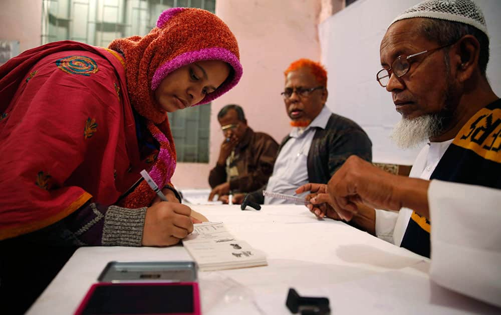 A Bangladeshi woman writes her signature to receive a ballot paper before casting her vote at a polling station in Dhaka, Bangladesh.