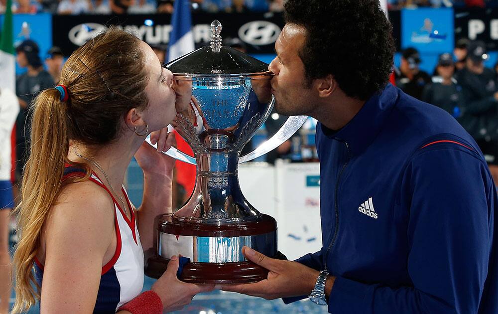 Alize Cornet, left, and team mate Jo-Wilfried Tsonga, right, of France, kiss the Hopman Cup after defeating Agnieszka Radwanska and Grzegorz Panfil at the Hopman Cup tennis tournament in Perth.
