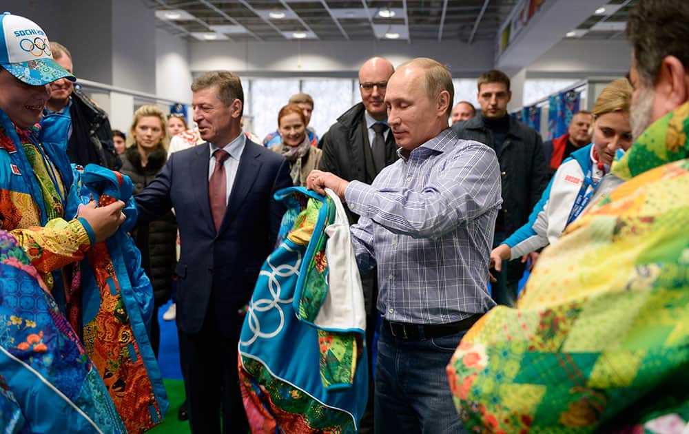 Russian President Vladimir Putin, center, tries on a jacket during a visit to the training center for volunteers Winter Olympics at the Black Sea resort of Sochi, southern Russia.