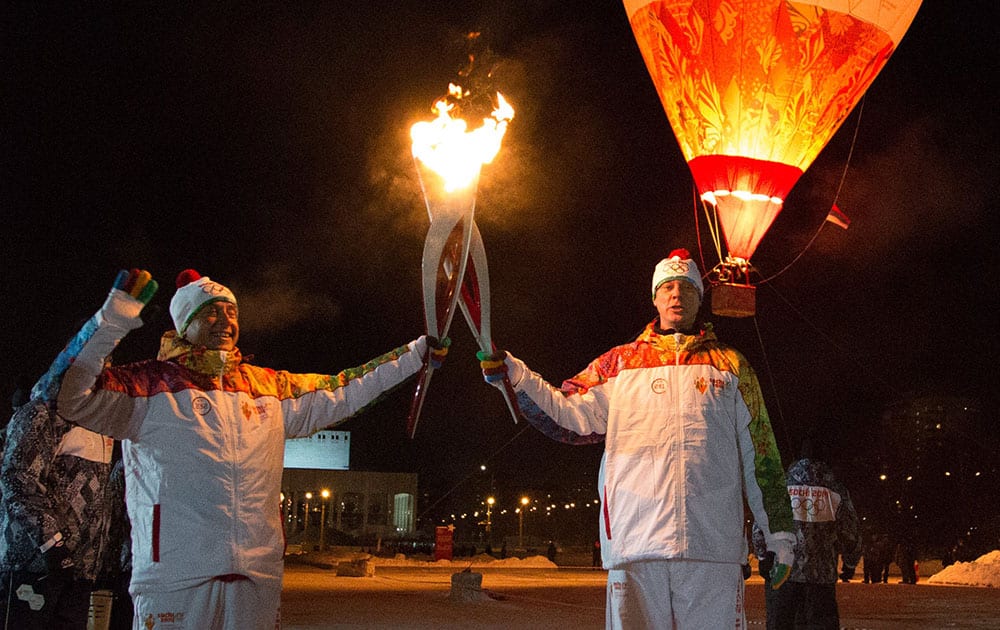Olympic torch bearers Alexander Tuchkin, left, and Vasiliy Makarov hold Olympic torches during the torch relay in Perm, Russia.