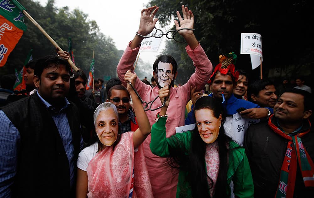 Activists of India’s main opposition Bharatiya Janata Party (BJP) pose wearing handcuffs and masks of former Delhi state chief minister Sheila Dikshit, foreground left, ruling Congress party President Sonia Gandhi, foreground right, and party Vice President Rahul Gandhi, during a protest against the Congress party and corruption charges against its leaders, in New Delhi.