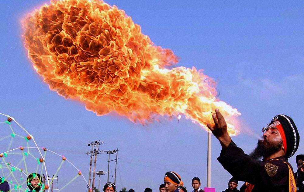 A Sikh youth blows fire out from his mouth during a religious procession ahead of the birth anniversary of 10th master of Sikh religion Guru Gobind Singh in Jammu.