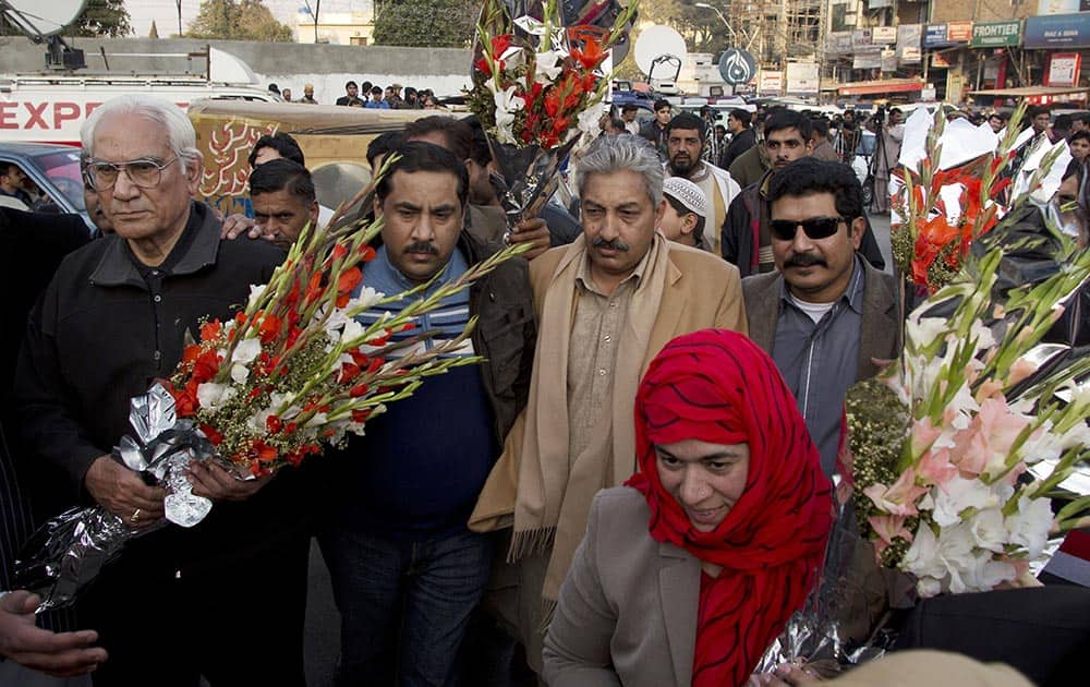Ahmed Raza Qasuri, left, attorney of Pakistan`s former president and military ruler Pervez Musharraf, carries flowers with Musharraf`s supporters outside a military hospital in Rawalpindi, Pakistan.