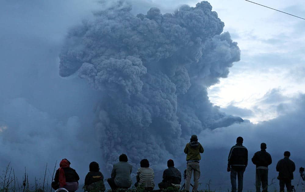 Indonesian men watch Mount Sinabung spewing volcanic materials during an eruption in Tiga Kicat, North Sumatra, Indonesia.