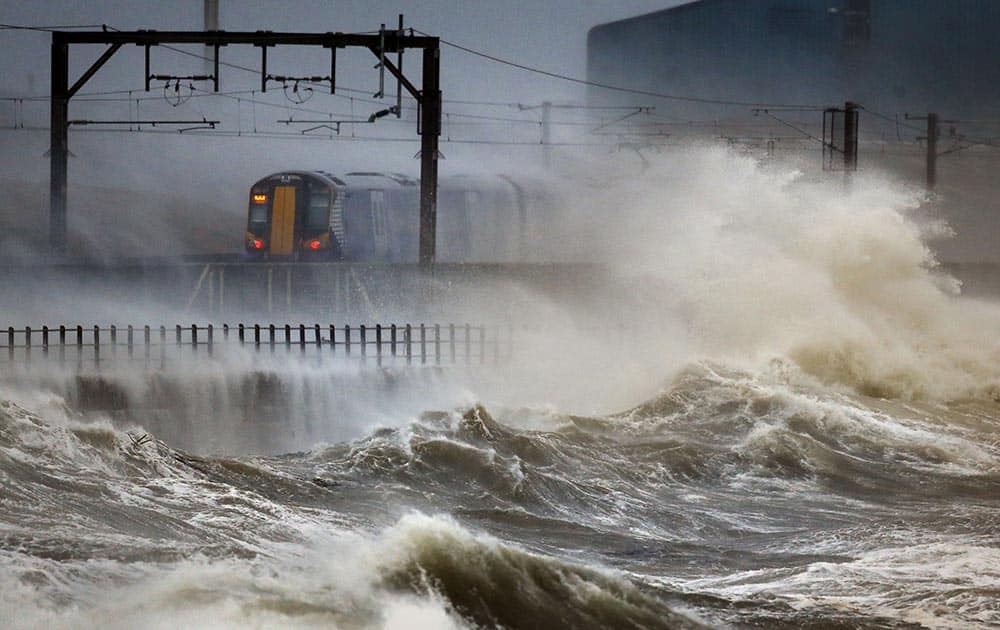 A train passes along the coast at Saltcoats in Scotland, Friday, Jan. 2014, as Britain is braced for the worst as a combination of high tides, heavy rains and strong winds are expected to bring yet more severe flooding to many parts of the country.