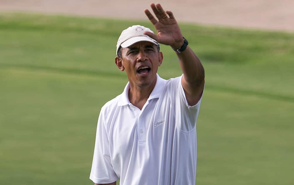 President Barack Obama waves to the crowd watching him play golf of the 18th green at the Mid Pacific Country Club, in Lanikai on the island of Oahu, in Hawaii.