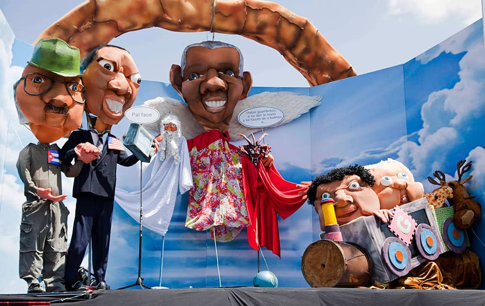 An effigy of Nelson Mandela, center, flanked by a message that reads in Spanish `Listen kids, hold hands and make up, or...` stands by statues of President Barack Obama holding a camera and the hand of Cuba`s President Raul Castro with the message in Spanish `For Facebook` on New Year`s Eve in Quito, Ecuador.