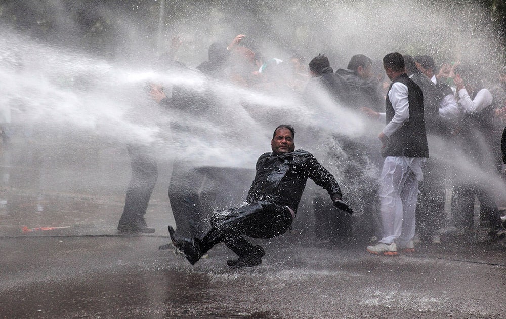 An activist of India’s main opposition Bharatiya Janata Party falls down as he and others are hit by police water cannon during a protest outside Congress party Vice President Rahul Gandhi`s residence in New Delhi.