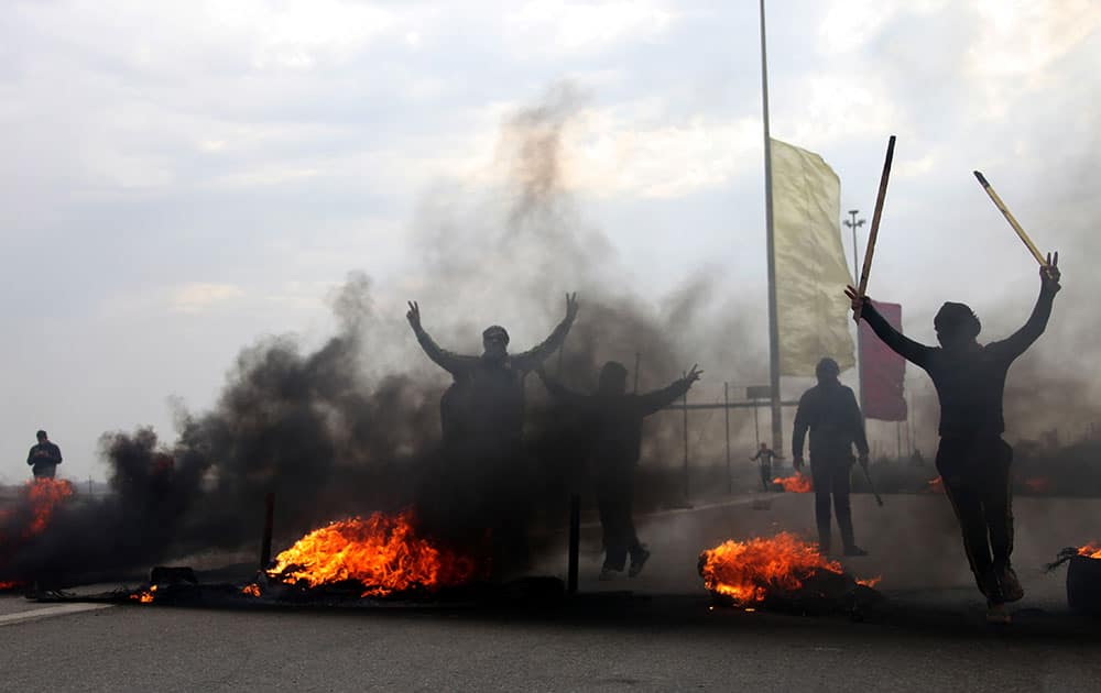 Iraqi Sunni masked protesters burn tires to blocked the main highway to Jordan and Syria, outside Fallujah, 40 miles (65 kilometers) west of Baghdad, Iraq.