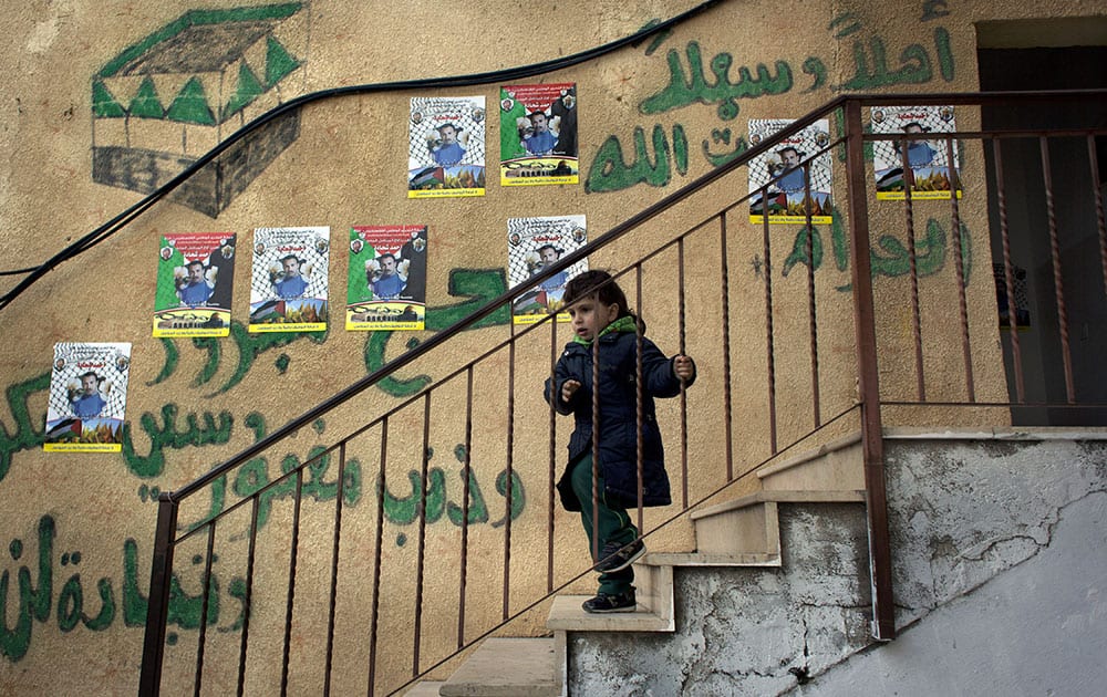 A child walks down the stairs of the family home of Ahmed Shehadeh, one of 26 Palestinian prisoners expected to be released later tonight, next to posters with his picture and Arabic that reads