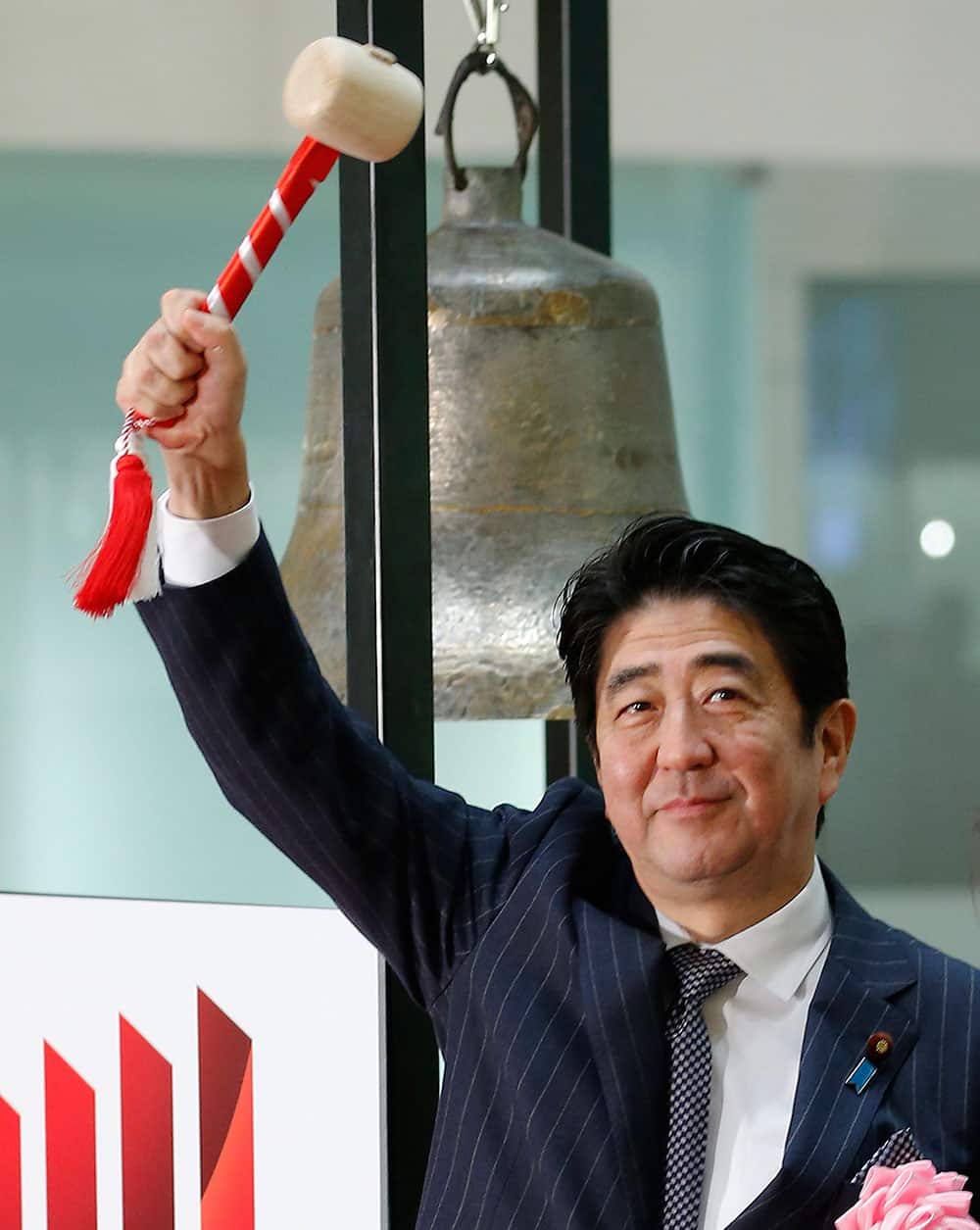 Japanese Prime Minister Shinzo Abe poses for photographers after sounding a bell during a ceremony marking the last session of the year 2013 at the Tokyo Stock Exchange in Tokyo.