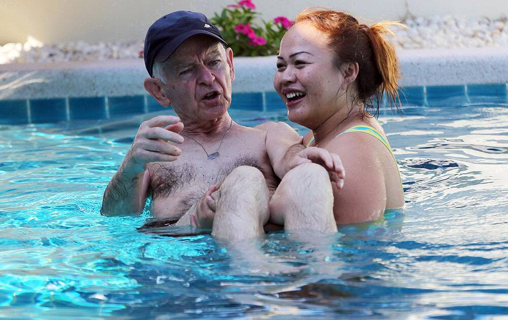 A Thai caretaker, right, carries Gerhard, an Alzheimer patient from Switzerland in a swimming pool at Baan Khamlangchai care center in Chiang Mai province, northern Thailand.