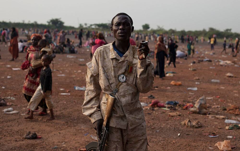 A Chadian soldier, part of an African peacekeeping force, smokes a cigarette as he stands guard over Chadians waiting for evacuation flights, at the airport in Bangui, Central African Republic.