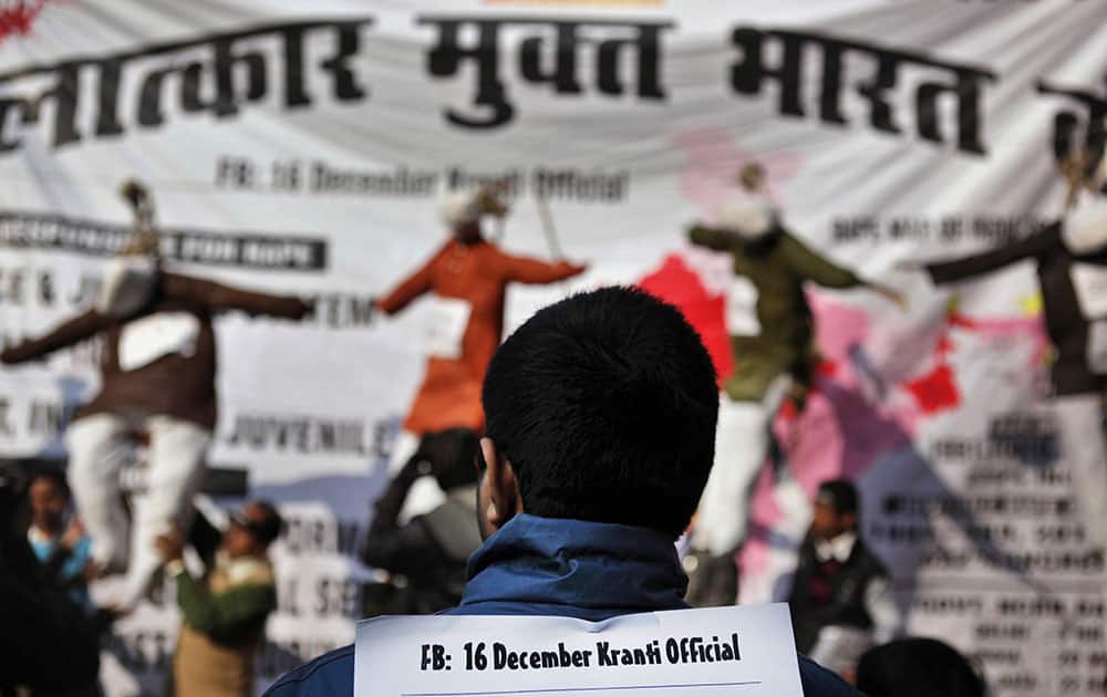 A man displays a placard on his back as he along with others marks the first anniversary of the fatal gang rape of a young woman, in New Delhi.